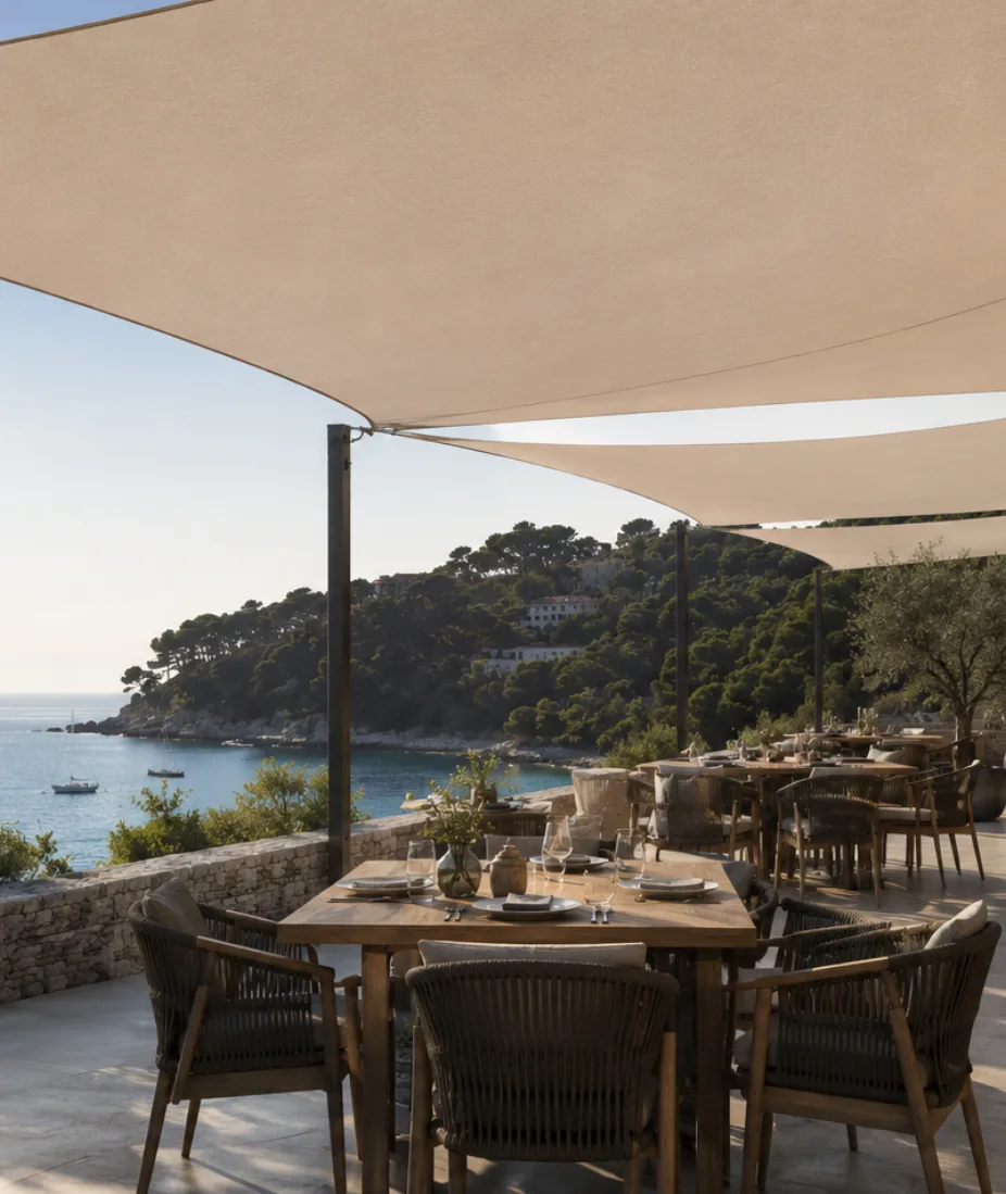 Voiles d'ombrage beiges tendues au-dessus d'une terrasse de restaurant en bord de mer